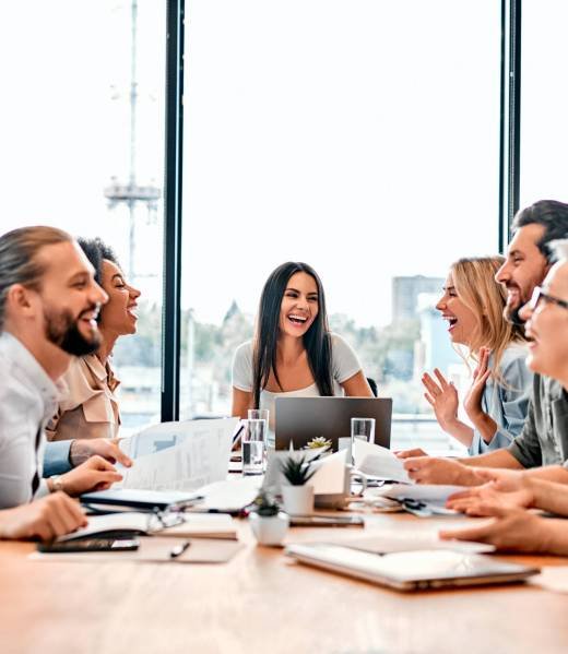 Having fun during meeting. Cheerful  employees laughing happily while sitting in meeting room with panoramic window. Female chief making joke for creating optimistic and friendly vibes. Copy space.